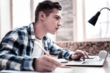 Çatık ve notlar yaparken ekrana bakarak meşgul öğrenci