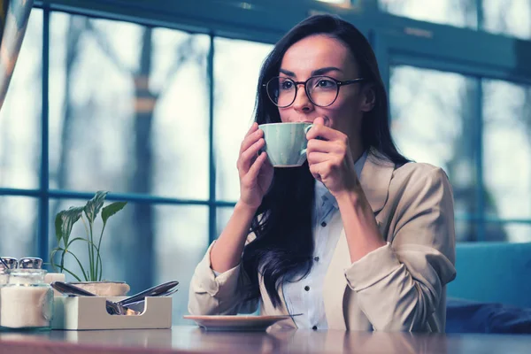 Концентрированная брюнетка-женщина проводит время в любимом кафе — стоковое фото