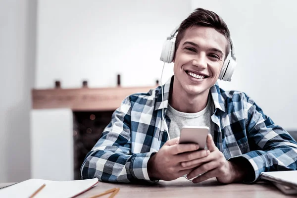 Hombre guapo escuchando música en auriculares y sonriendo — Foto de Stock