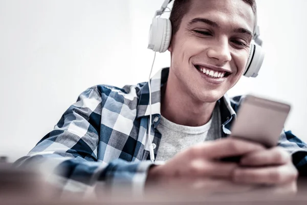 Ontspannen jongeman glimlachend en luisteren naar muziek in hoofdtelefoons — Stockfoto