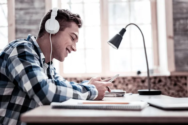 Schöner Student, der Musik hört, während er Hausaufgaben macht — Stockfoto