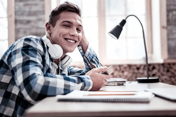 Handsome student relaxing while doing homework and smiling — Stock Photo, Image