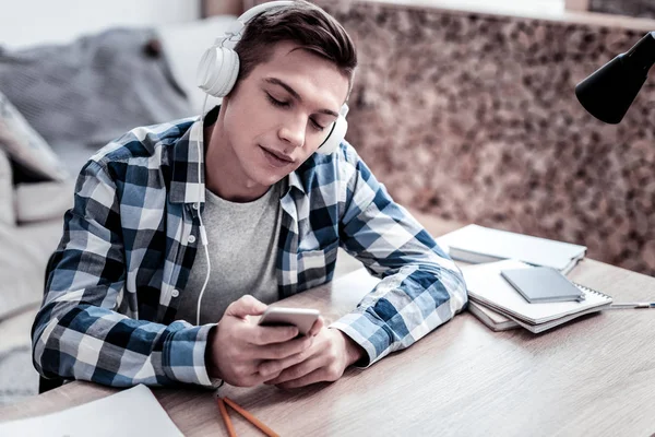 Homem calmo olhando para seu smartphone enquanto escolhe a música — Fotografia de Stock