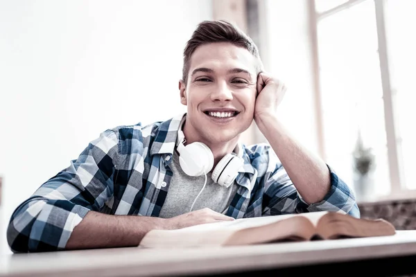 Homem alegre relaxando e sorrindo feliz enquanto sentado com seu livro — Fotografia de Stock