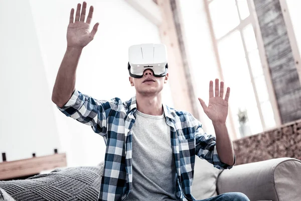 Koncentrerad person att sätta händerna upp medan du använder virtual reality-glasögon — Stockfoto