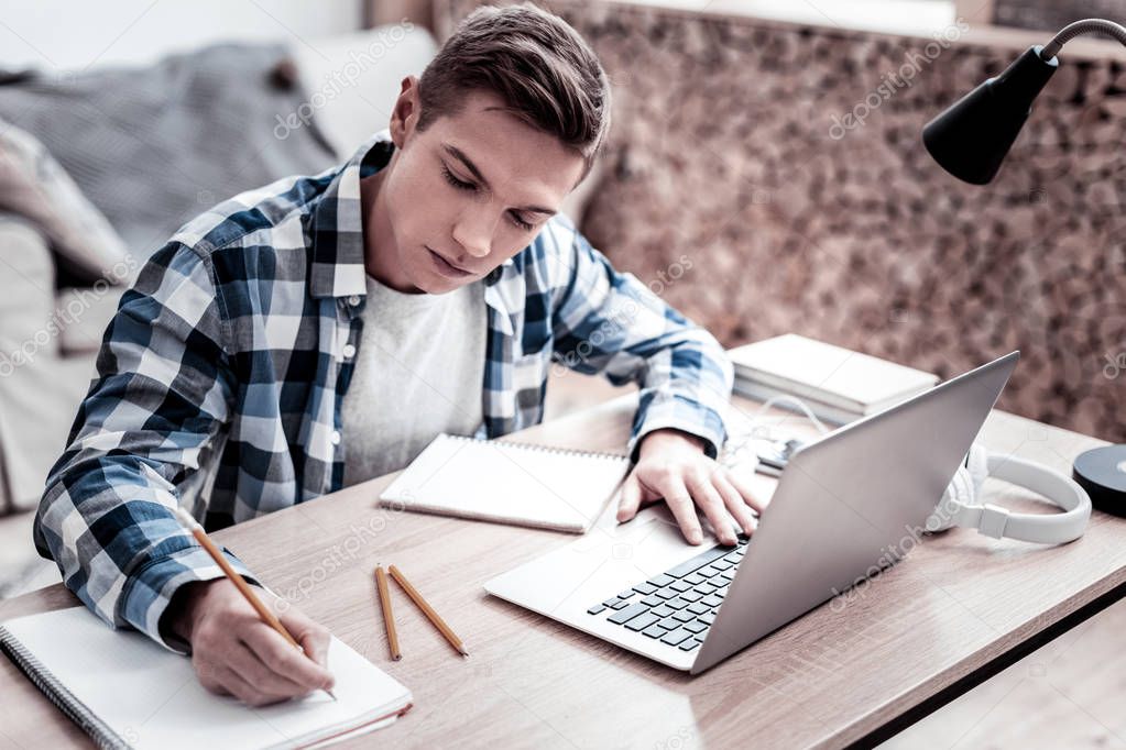 Attentive student making notes while doing homework