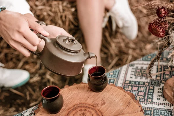 Gros plan des mains masculines qui versent le thé dans la tasse — Photo