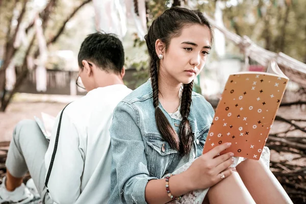 Concentrated brunette girl reading romantic story in park — Stock Photo, Image