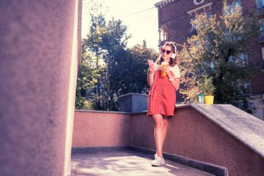 Parlak kırmızı güneş gözlüğü ve beyaz kulaklık giyen sevimli komik çekici kız