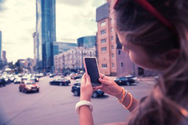 Şehir fotoğrafı yaparken akıllı telefonunu kullanarak genç şehir blogger