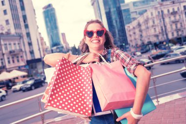 Çanta giysileri ile. Genel olarak pek çok ağır çantaları giysileri ile tutarak gülümseyen kırmızı güneş gözlüğü takıyor moda kadın