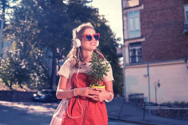 Glad positiv tjej som kommer till hennes föräldrars hus med lilla hem växt — Stockfoto
