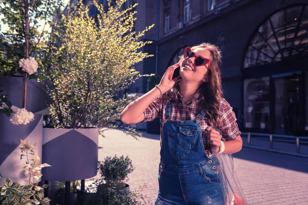 Lycklig kvinna bär snygga casual kläder tala via telefon med hennes vän — Stockfoto