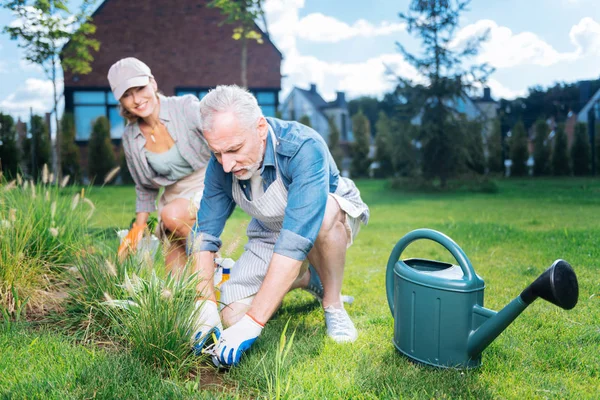 Barbuto marito dai capelli grigi sostenere e aiutare la moglie nel letto da giardino — Foto Stock