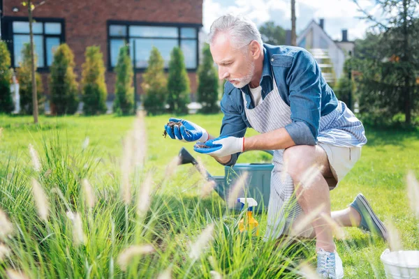 Hombre barbudo con pantalones cortos beige y zapatillas de deporte que enriquecen el suelo en el jardín — Foto de Stock