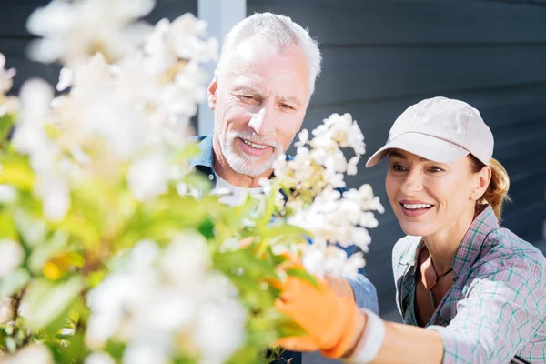 Stralend vrolijke man en vrouw die permanent in de buurt van hun bloeiende boom — Stockfoto