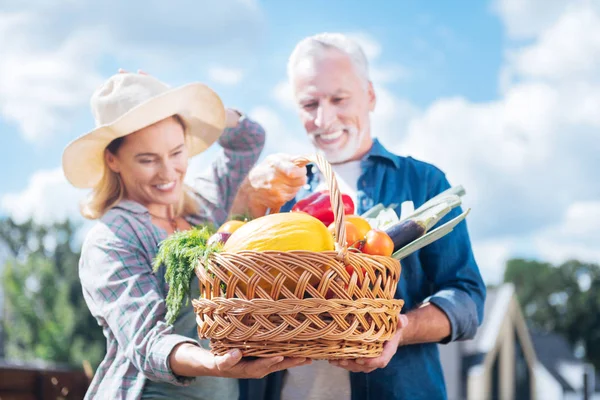 Esposo y esposa sonriendo mientras miran las verduras desde su cama de jardín — Foto de Stock