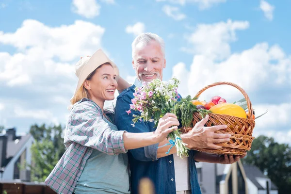 Седовласый заботливый муж чувствует себя хорошо после того, как подарил полевые цветы своей жене — стоковое фото