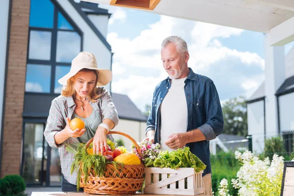 Apelando ama de casa celebración agradable naranja fresca después de comprar comida con el marido — Foto de Stock