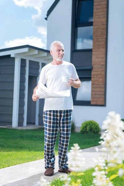 Mann steht in seinem gemütlichen Hof und liest interessante Morgennachrichten — Stockfoto