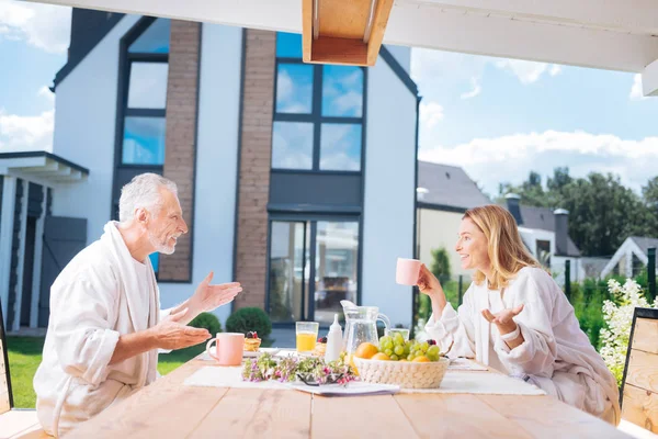 Feliz casal irradiando ter uma conversa emocional enquanto toma seu café da manhã — Fotografia de Stock