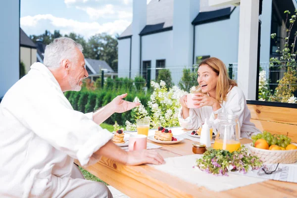 Schöne Frau lacht, während sie mit ihrem Mann frühstückt — Stockfoto