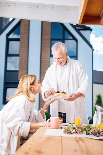 Красива дружина бере тарілку з фруктовими млинцями від свого турботливого чоловіка — стокове фото