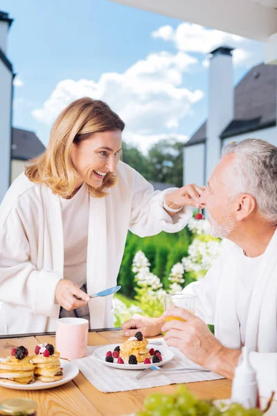 Amante casal radiante vestindo roupões de banho brancos tomando café da manhã fora — Fotografia de Stock
