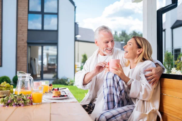 Cute couple of mature man and woman laughing while joking during breakfast