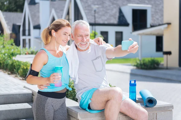 Skäggiga mogen man håller hans blå telefonen samtidigt selfie med fru — Stockfoto