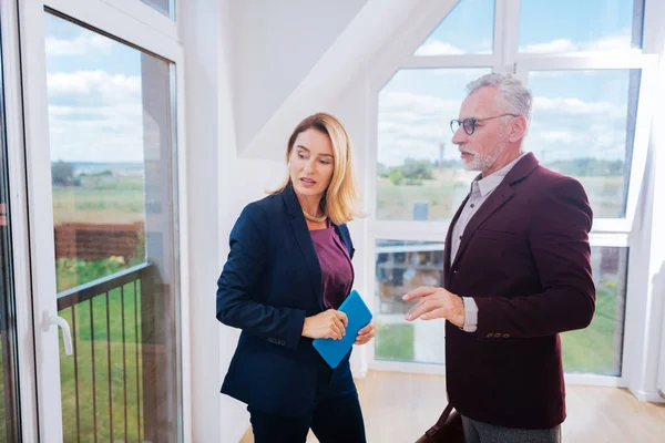 Blonde-haired onroerende goederenagent beschrijven ruime moderne huis haar cliënt — Stockfoto