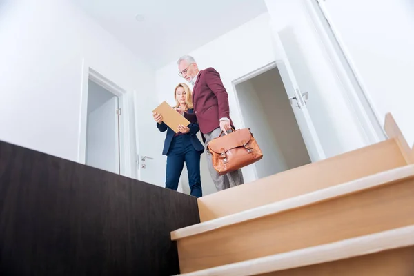 Ervaren stijlvolle onroerende goederenagent tonen haar rijke cliënt appartement plan — Stockfoto