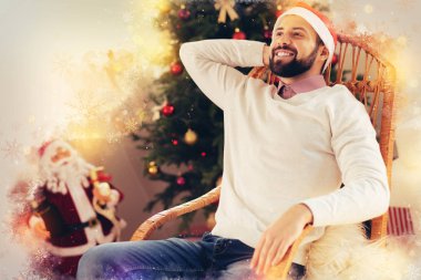 Noel ağacı oturma odasında yakın sandalyede otururken yakışıklı gülen