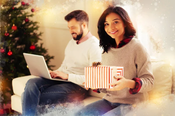 Épouse attrayante portant un pull gris tenant une jolie boîte cadeau de Noël rouge — Photo