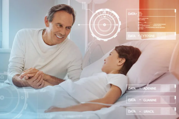 Kind father smiling and holding a hand of his tired ill daughter — Stock Photo, Image