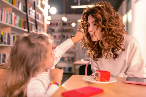 Mujer morena alegre comiendo sabroso postre en la cafetería —  Fotos de Stock