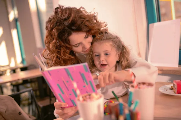 Маленькая добрая девочка смотрит на свою книгу с рассказами — стоковое фото