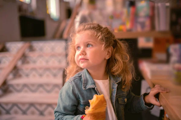 Encantadora niña comiendo pastelería fresca en la cafetería —  Fotos de Stock