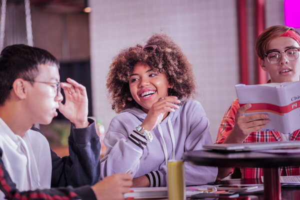 Веселая интернациональная девушка смеется над смешной шуткой
