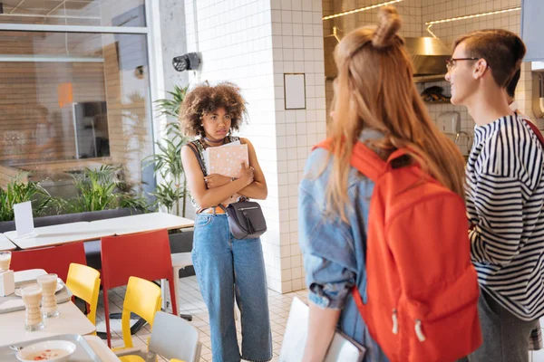 Chica de piel oscura asustada sosteniendo libros en ambas manos — Foto de Stock