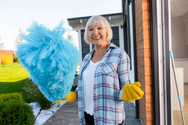 Beaming blonde-haired elderly lady doing cleaning near summer house — Stock Photo, Image