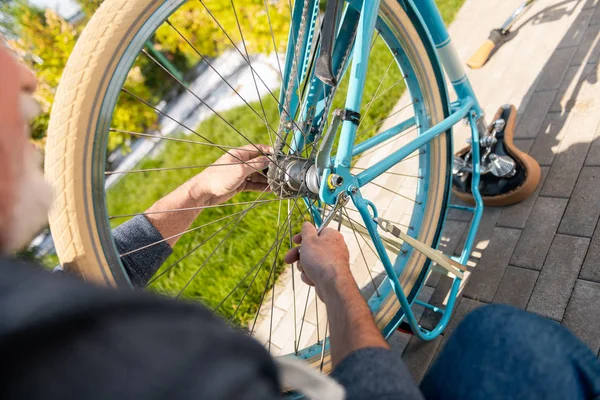 Top view of mature man repairing old-fashioned blue bicycle outside the house — Stock Photo, Image