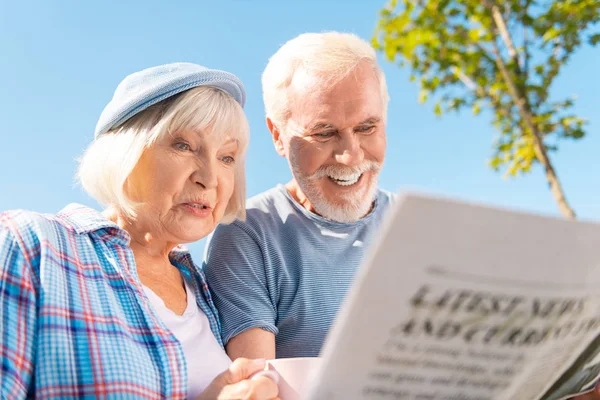 Abuela y abuelo viendo la historia de sus nietos en el periódico —  Fotos de Stock