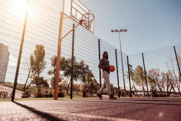 Positivo homem alegre andando na quadra de basquete — Fotografia de Stock