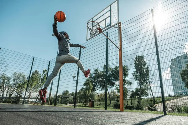 Bom homem forte pulando enquanto joga uma bola — Fotografia de Stock