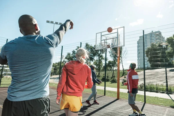 Hombre hábil guapo lanzando una pelota desde la distancia — Foto de Stock