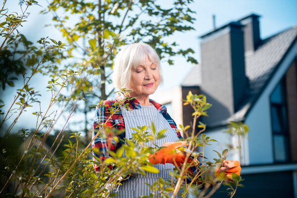 Мысли. Красивая старушка думает, стоя в саду
