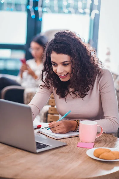 Positive nette Frau, die Notizen im Notizbuch macht — Stockfoto