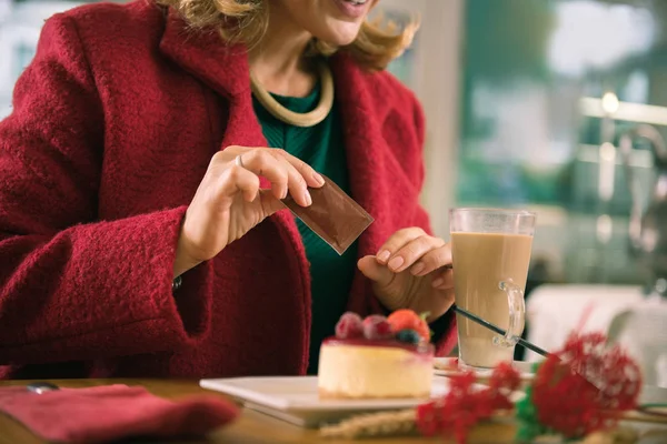 Blonde-Haired nő visel zöld ruhát, és a piros kabát üzembe cukor, a kávé — Stock Fotó