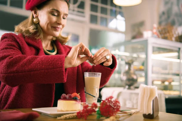 Elegante Französin fügt etwas Zucker in ihren Latte hinzu — Stockfoto